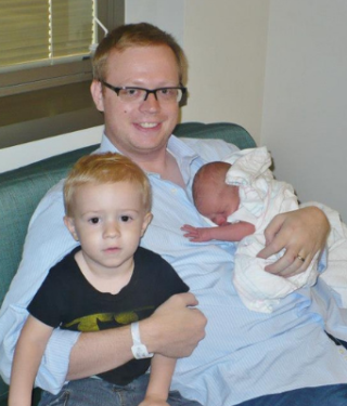 new dad holding newborn baby and son