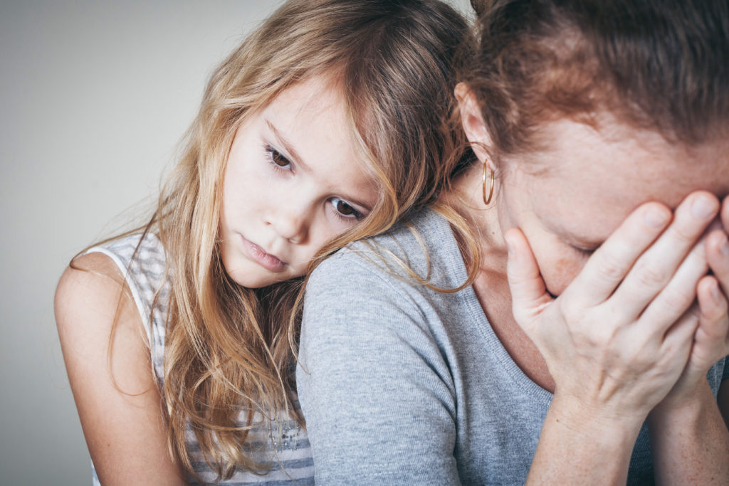 depressed mother struggling with mental health being comforted by a child
