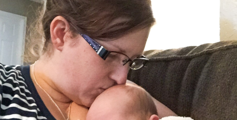 Mom kissing newborn's head grieving a newborn experience she didn't have